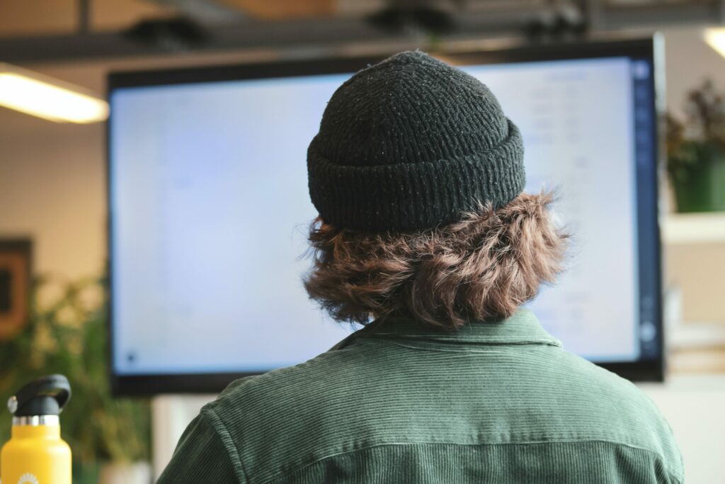 Man wearing beanie looking at large tv with powerpoint on display